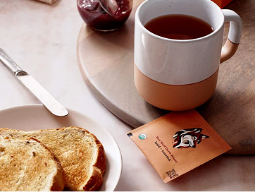 Goldholly Dark Roast Yaupon teabag beside a mug of brewed tea and toast on a breakfast plate