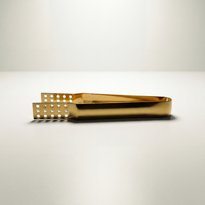 Closeup of golden metal teabag tongs on a white background.